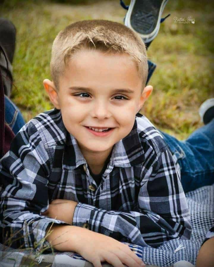Colton smiling outdoors in a plaid shirt